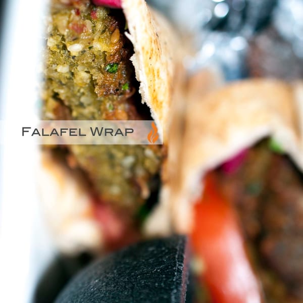 Close-up of a Byblos falafel wrap, showing crispy falafel, fresh vegetables, and pita bread.