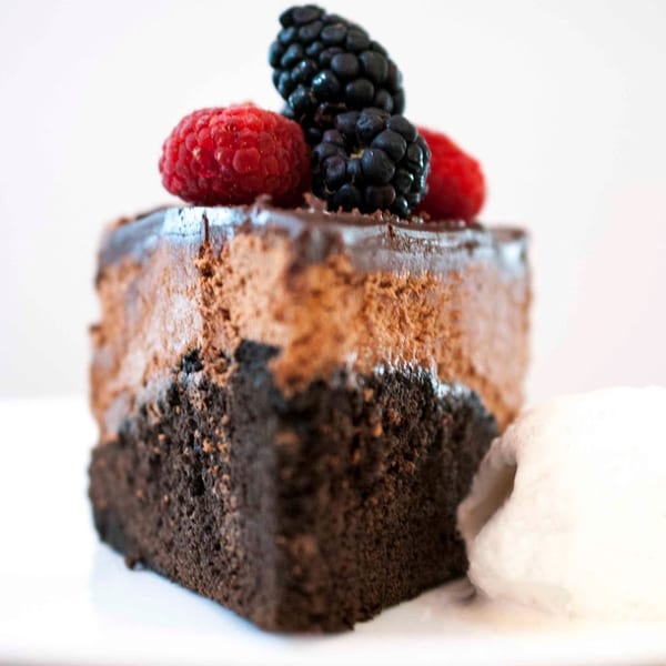 Byblos' chocolate mousse cake with fresh raspberries and blackberries on top, next to a dollop of cream.