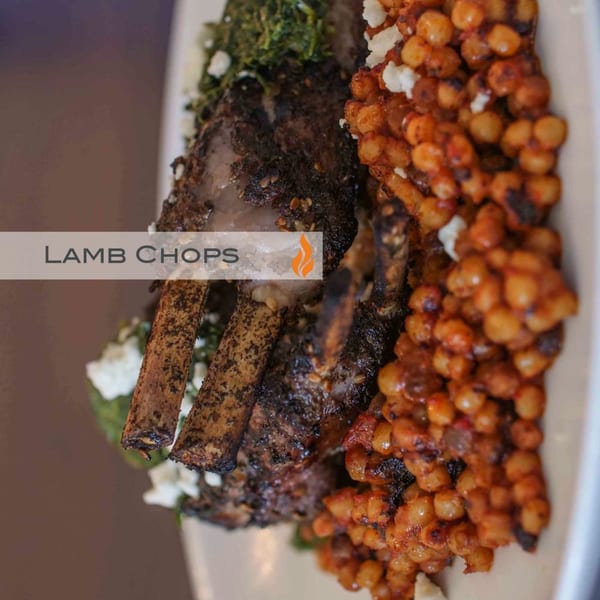 Byblos' Mediterranean lamb chops with green herbs, feta, and spiced chickpeas on a white plate.