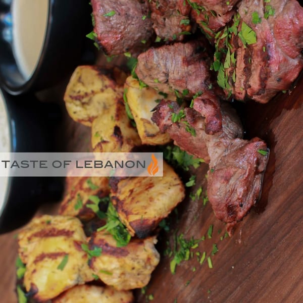 Grilled meat and chicken pieces garnished with parsley, served with dipping sauces at Byblos.