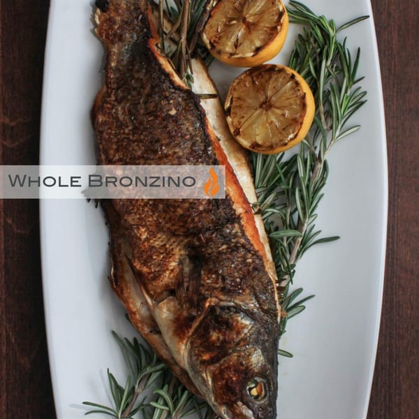 Byblos' whole bronzino, grilled and garnished with rosemary sprigs and charred lemon halves.