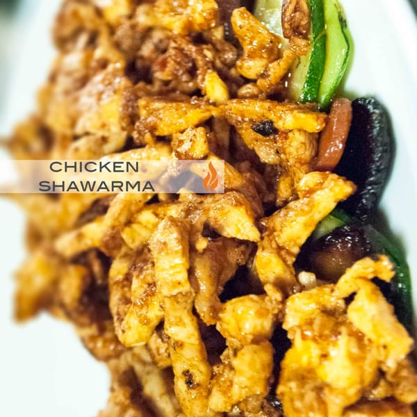 Close-up of Byblos' chicken shawarma with sliced cucumbers and dark olives.