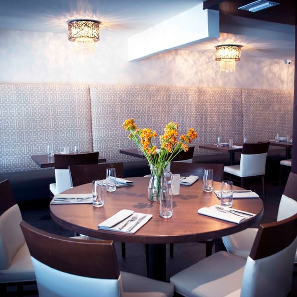 Byblos Mediterranean restaurant interior with set tables, patterned banquettes, and decorative chandeliers.