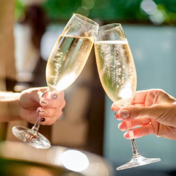 Two hands holding champagne flutes, clinking them together in a toast.