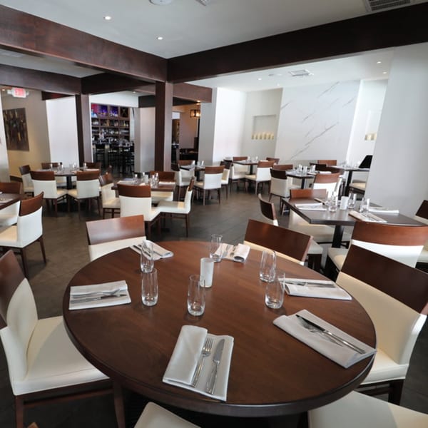 Byblos Mediterranean restaurant interior with set tables, white chairs, and dark wood accents.