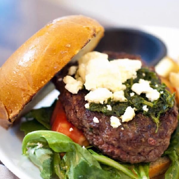 Byblos Mediterranean burger with feta, spinach, tomato, and greens on a bun.