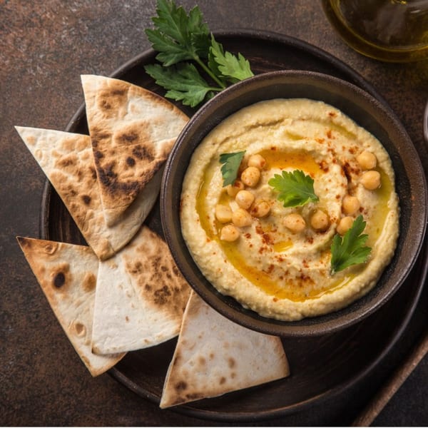 Byblos Mediterranean hummus with chickpeas, olive oil, and parsley, served with pita bread.