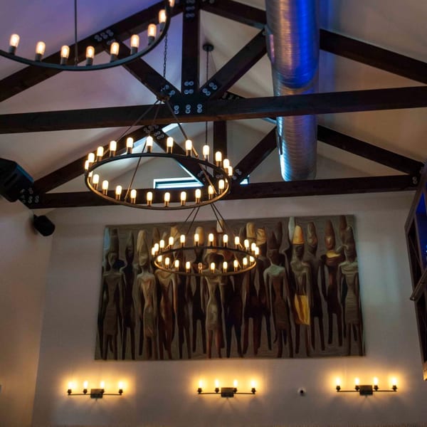 Byblos restaurant interior with large circular chandeliers, exposed wooden beams, and a textured wall art.