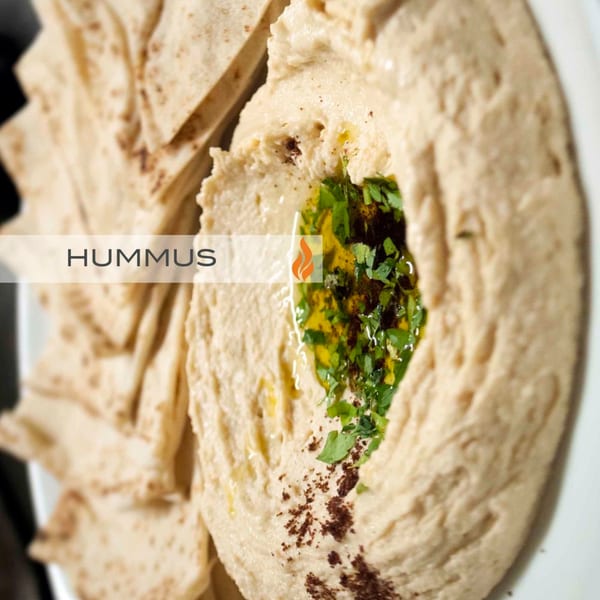 Creamy hummus drizzled with olive oil, herbs, and spices, served with pita bread.